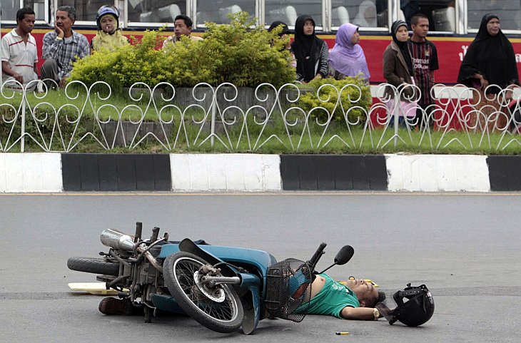 Люди смотрят на тело тайской человека, застреленного повстанцами
