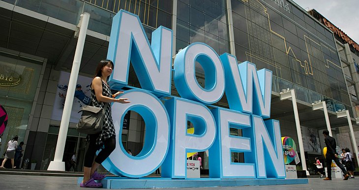 Женщина фотографируется на фоне гигантских букв «Мы открылись» около Центрального универсального магазина в Бангкоке