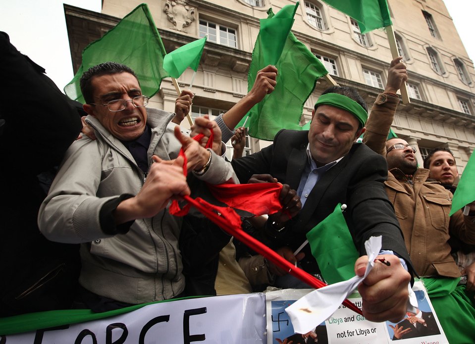 Сторонники Муамара Каддафи рвут флаг, отобранный у мятежников