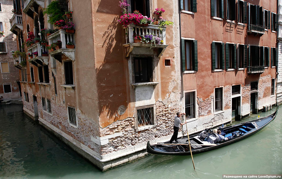 Гондольер катает туристов по каналам Венеции