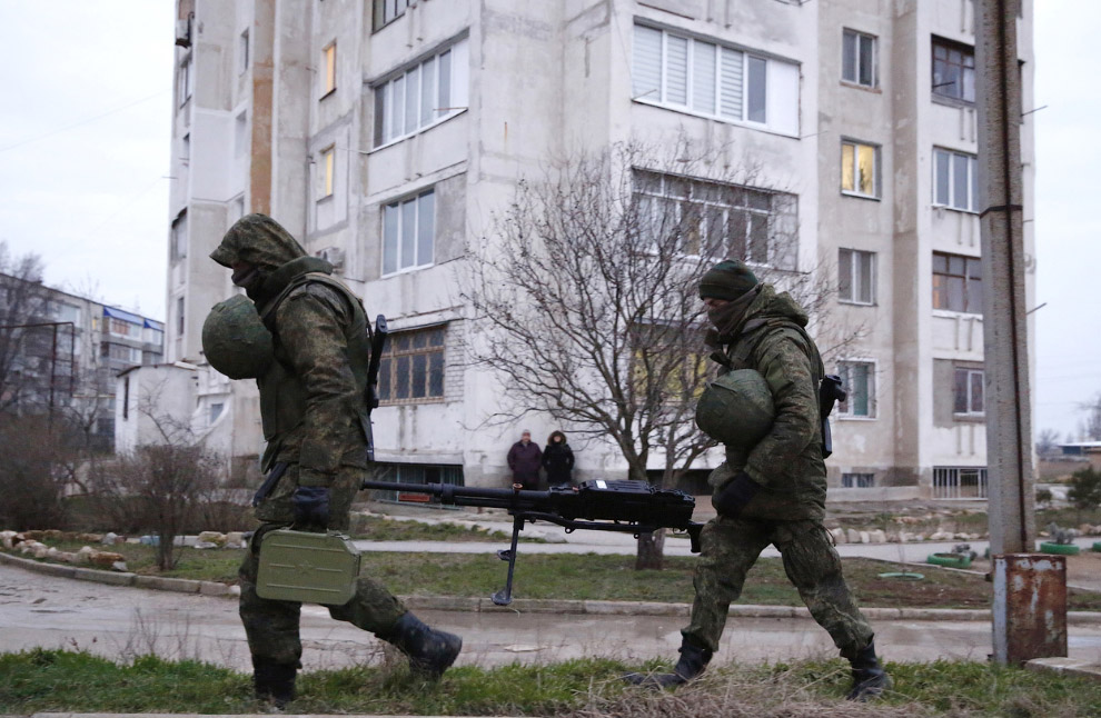 Предположительно российские солдаты несут тяжелый пулемет около украинской военной базы в Евпатории