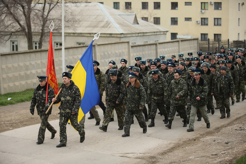 Украинские войска с украинским флагом идут навстречу российским солдатам, оккупировавшим авиабазу Бельбек