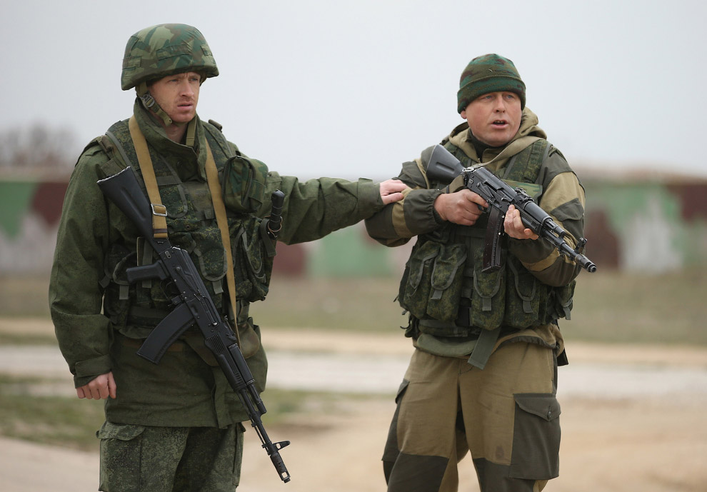 Один российский военный сдерживает другого, стрелявшего в воздух и приказывающего повернуть назад группе из более чем 100 невооруженных украинских солдат возле авиабазы Бельбек
