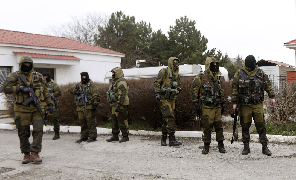 Вооруженные люди, предположительно российские военнослужащие, стоят у входа воинской части в Симферополе