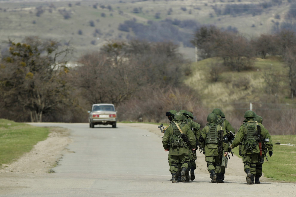 Вооруженные люди, предположительно российские военнослужащие, идут недалеко от военной базы в селе Перевальное