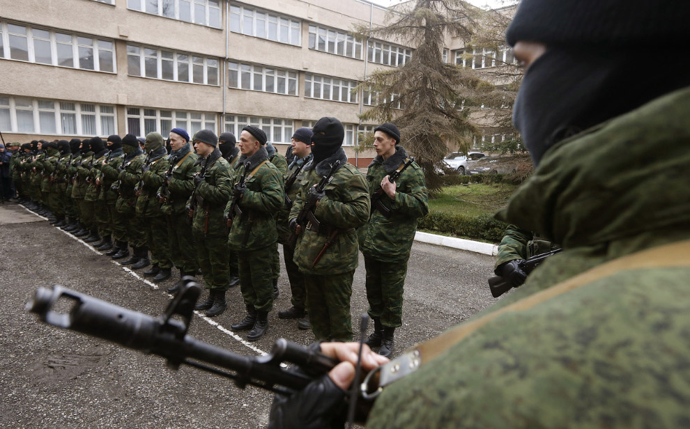 Вооруженный человек, предположительно российский военный (справа), и пророссийский отряд самообороны во время присяги на верность крымскому правительству