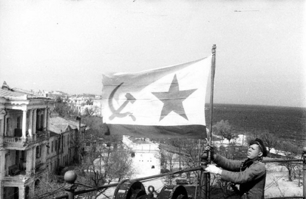 Морской пехотинец устанавливает советский военно-морской флаг в освобожденном Севастополе