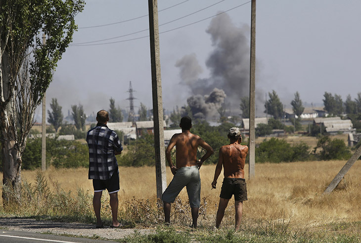 Местные жители и дым от обстрела в городе Новоазовске на востоке Украины