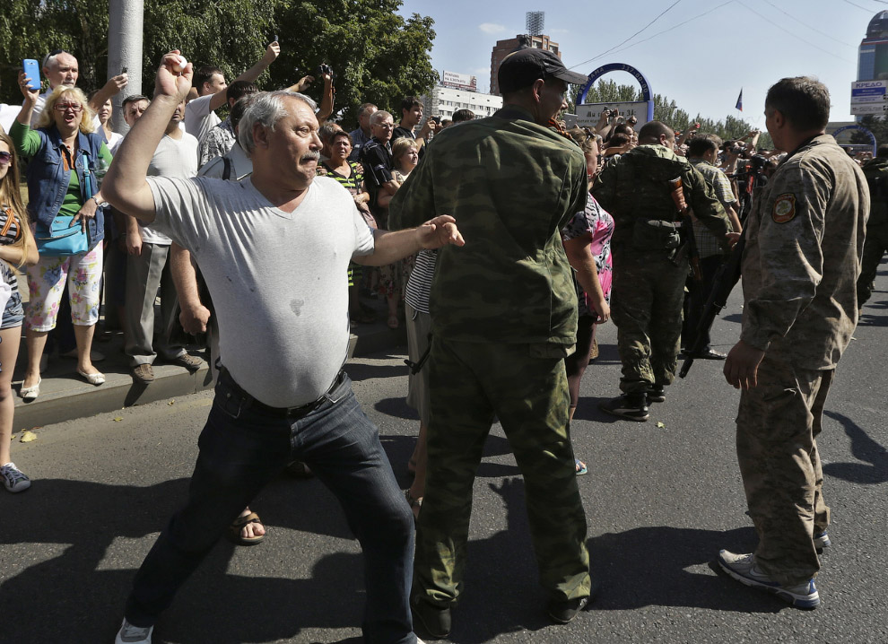 Человек бросает яйцо в украинских солдат во время «парада военнопленных» в Донецке