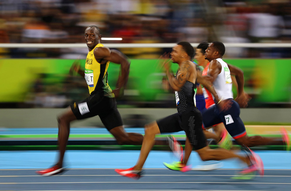 Усэйн Болт из Ямайки с улыбкой обходит своих конкурентов на 100-метровке