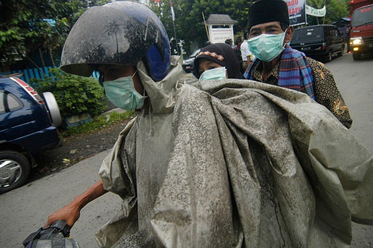 Жители покидают свои дома на мотоциклах после очередного извержения вулкана Мерапи в Клатене, Индонезия