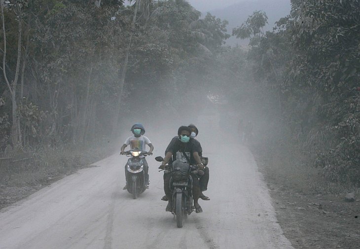 Жители покидают свои дома на мотоциклах после очередного извержения вулкана Мерапи в Клатене, Индонезия