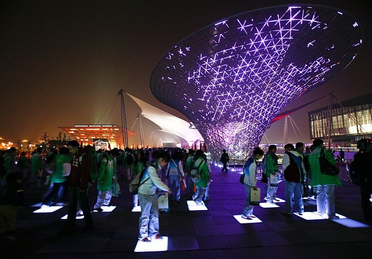 Люди играют на освещенных плитках около Экспо-центра после церемонии закрытия World Expo 2010