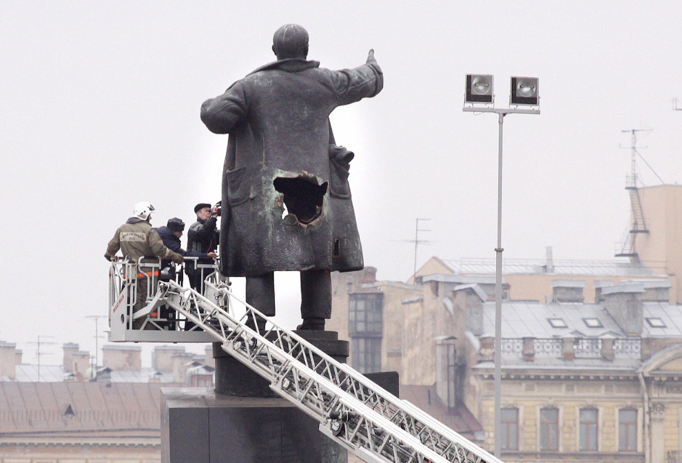 Эксперты-криминалисты изучают отверстие от взрыва бомбы, заложенной в памятник Владимиру Ленину в Санкт-Петербурге