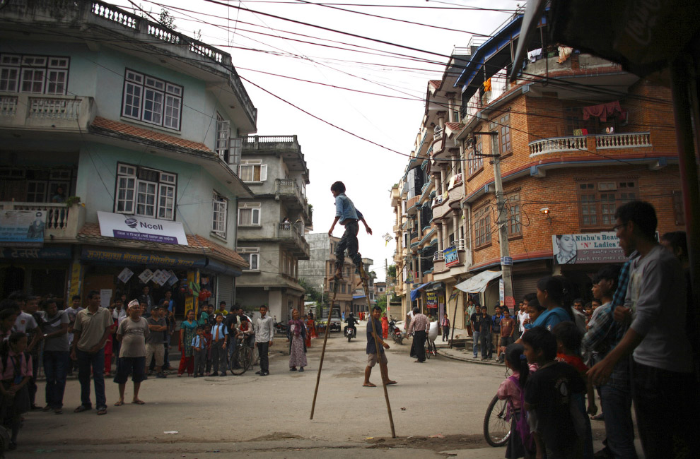 Мальчик на деревянных ходулях на улице в Катманду