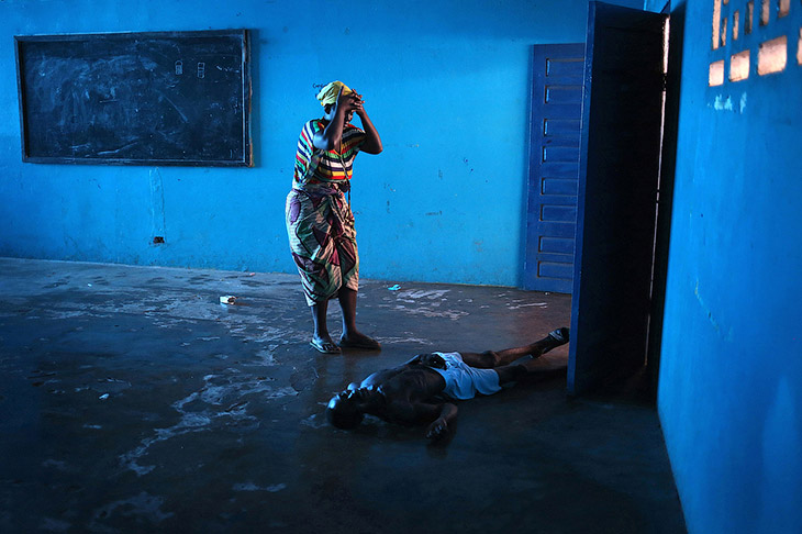 Монровия, Либерия. Заразившийся муж упал без сознания, жена стоит рядом