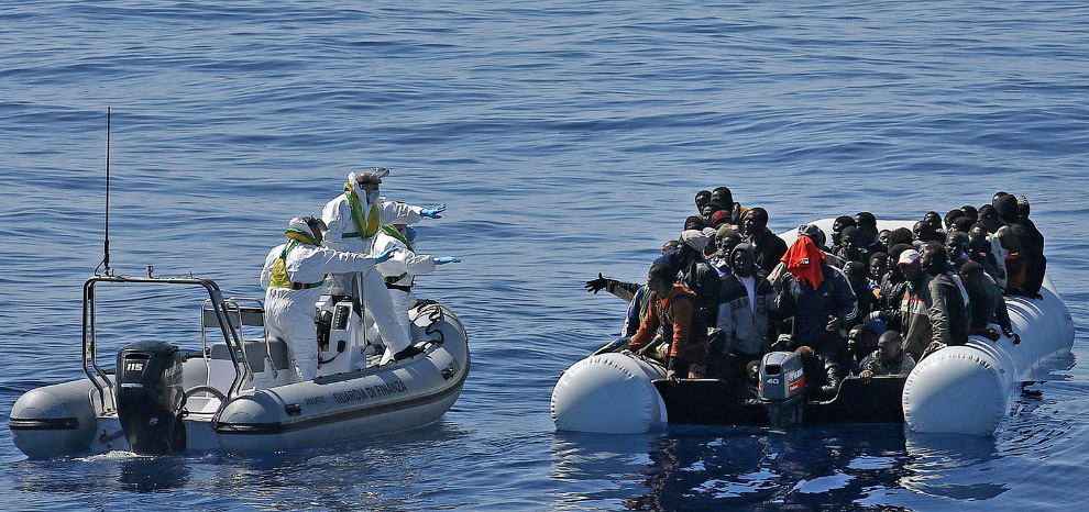 Судно с мигрантами и итальянская береговая охрана у берегов Ливии в Средиземном море