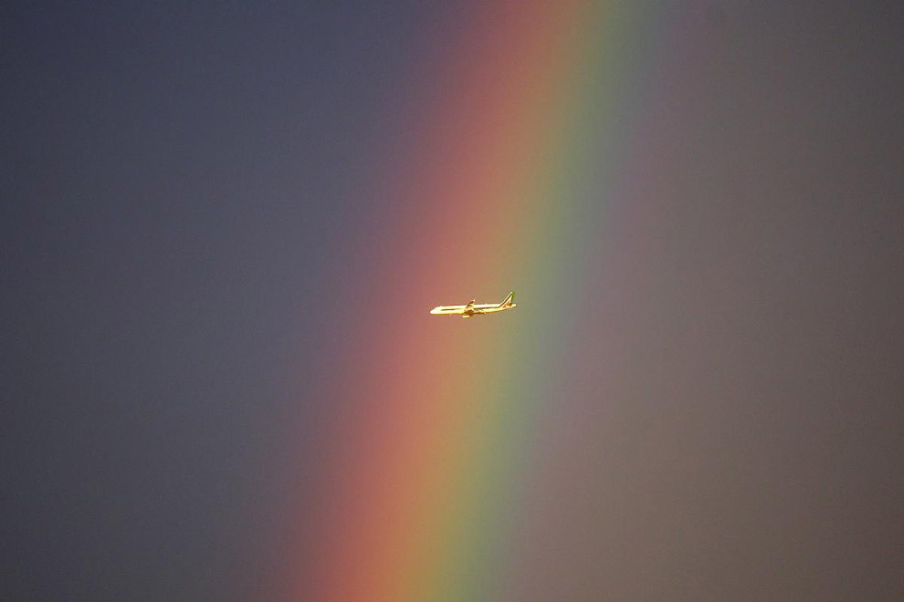 Самолет и радуга в небе недалеко от Милана, Италия