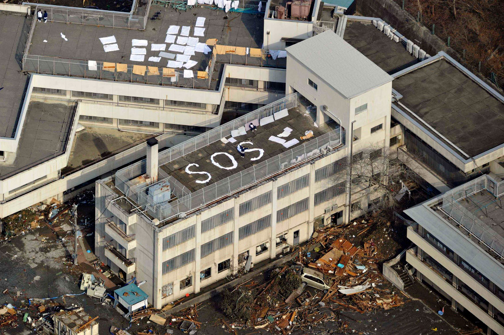 Люди из бумаги выложили слово SOS на крыше здания в Кесеннуме, префектура Мияги