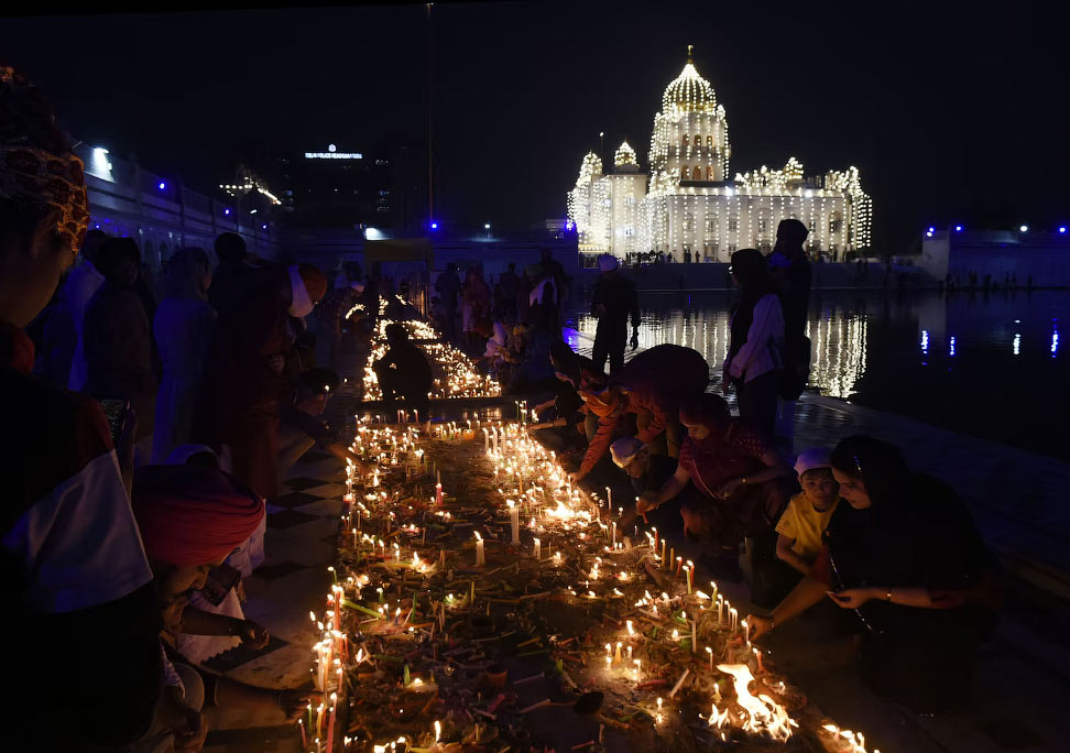 Сикхи зажигают свечи на закате во время фестиваля Дивали