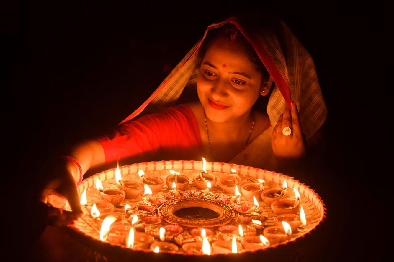 Женщина зажигает глиняные светильники по случаю Дивали