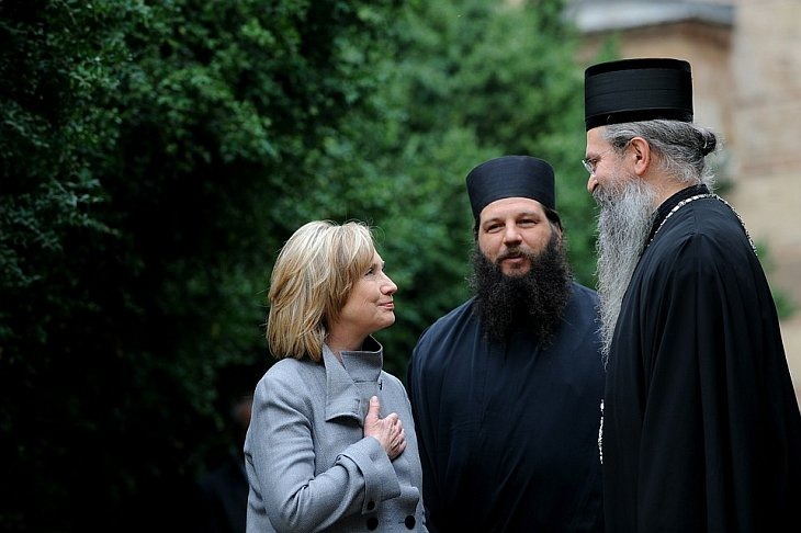 Государственный секретарь США Хиллари Клинтон говорит с епископом Феодосием (справа) во время своего визита в монастырь в Грачанице в Косово