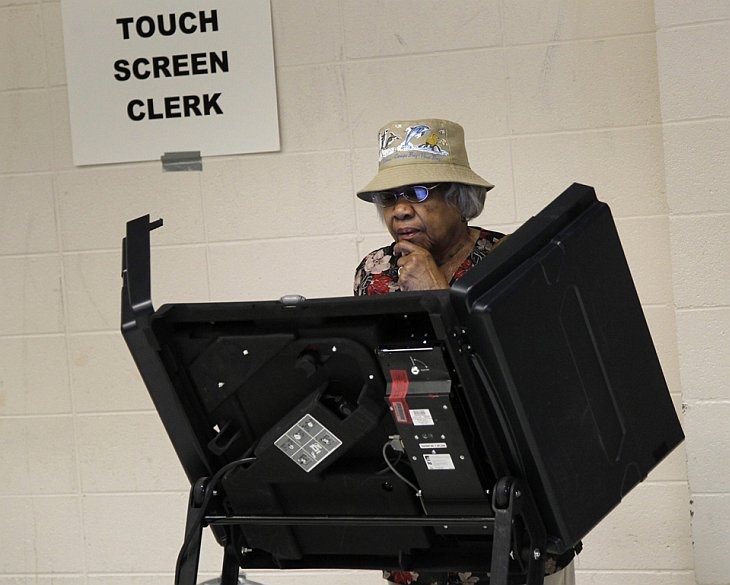 Женщина стоит перед электронной машиной для голосования